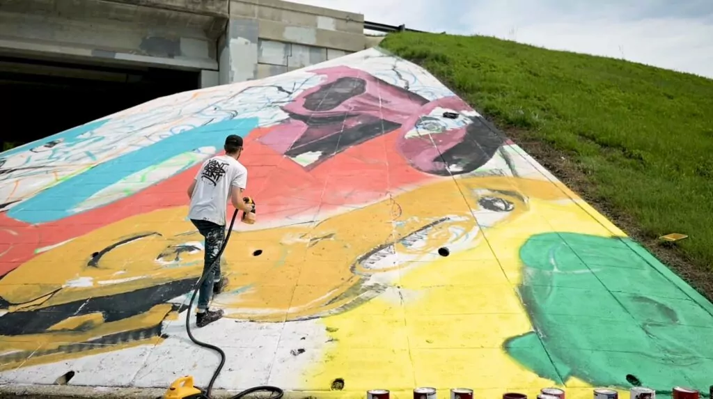 Still of an artist painting a mural from the Skatepark Underpass video.