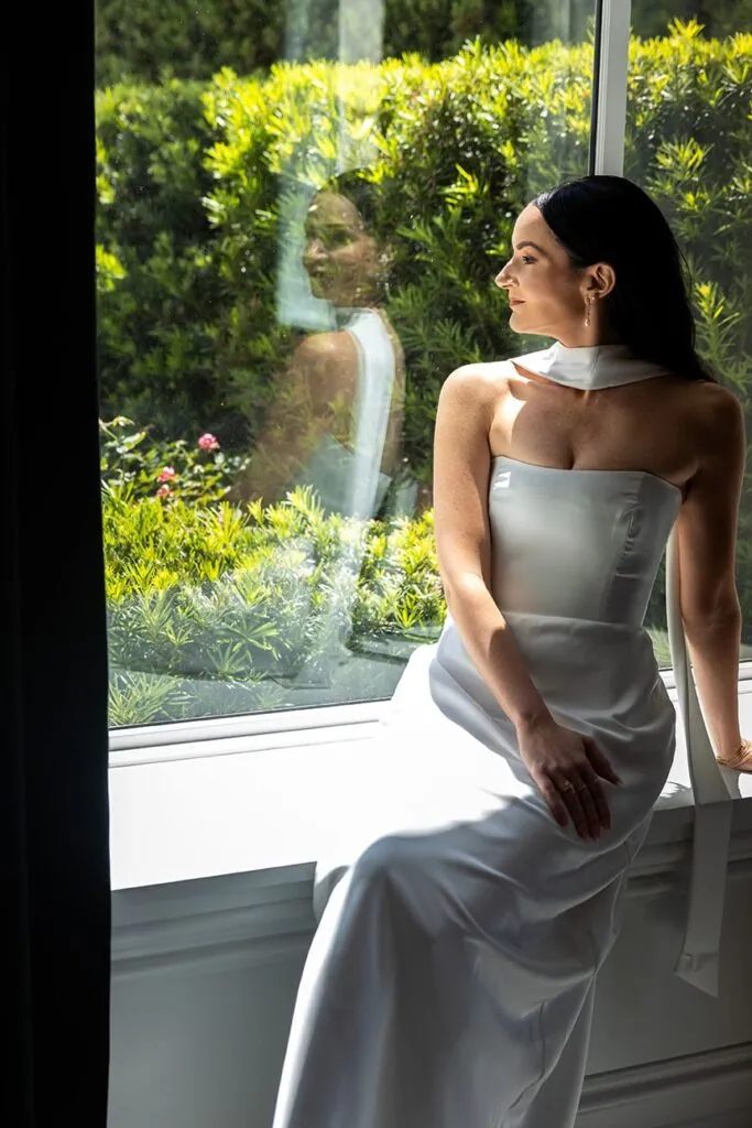 photo of woman in wedding dress looking out a window
