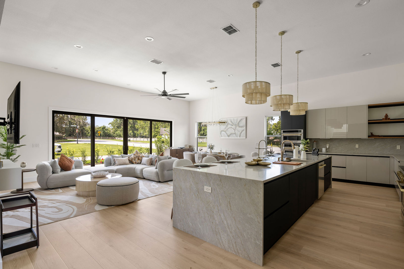 Open kitchen and living room at Livingston Park with a stone waterfall island, pendant lighting, and large windows