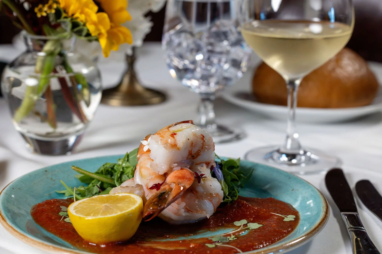 Shrimp with lemon, greens, and red sauce on a turquoise plate at Mark’s Prime in Ocala